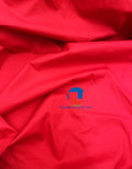 A solid red piece of cotton fabric with a small branding logo in the bottom corner.