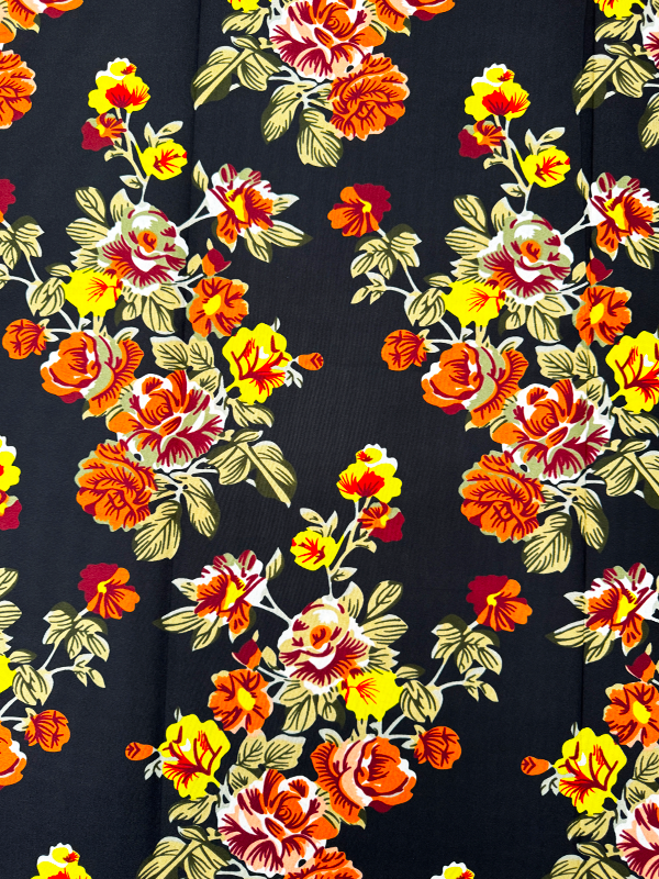 A piece of polyester fabric with a floral print in orange, yellow, white, and black colors on a dark background.