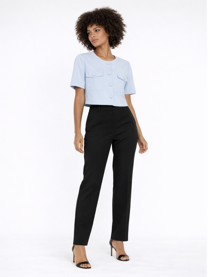 A model poses in a light blue cropped top with button details and two front pockets, paired with black trousers.