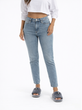 A person wearing light blue high-waisted jeans and gray fuzzy slides, standing against a plain white background.