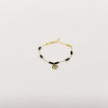 Golden curb chain anklet with black beads and peace sign charm, minimalist summer jewelry for women.