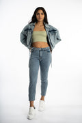 Model wearing Aubri oversized blue washed denim jacket with vintage street style vibe over light green crop top.