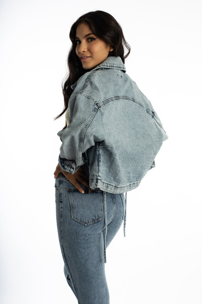 Model wears the Aubri oversized blue wash denim jacket with a vintage streetwear fit, back view on white background.