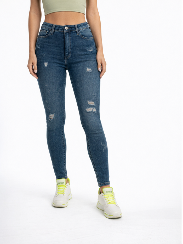 A woman wearing a cropped green top and distressed blue skinny jeans, paired with white sneakers featuring neon accents.