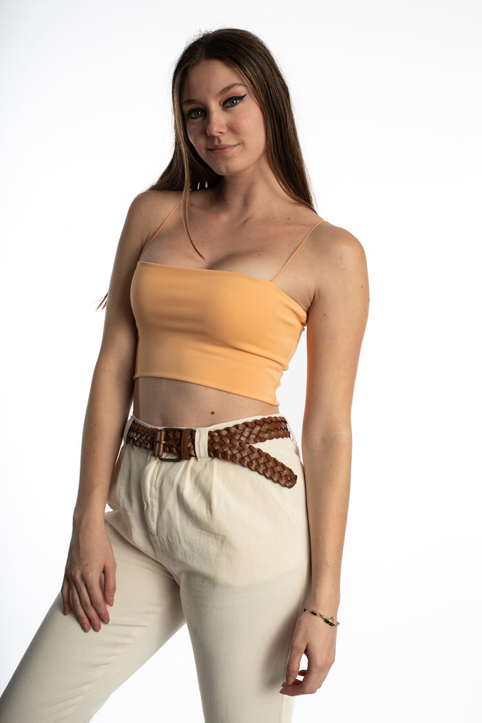 Model wears a peach Bailey Ribbed Crop Tank with spaghetti straps and cream trousers against a white studio background.