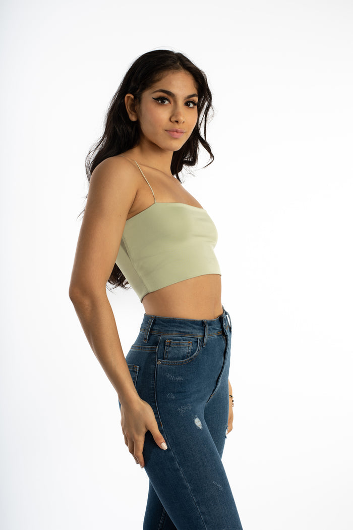 Model in Sage Green Bailey Ribbed Crop Tank with spaghetti straps and high-waisted distressed denim jeans.
