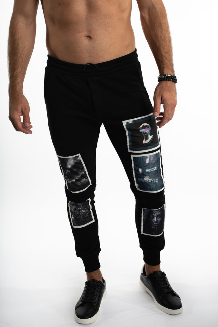 Men's black distressed streetwear joggers featuring graphic blind frame patches and a slim fit tapered leg.
