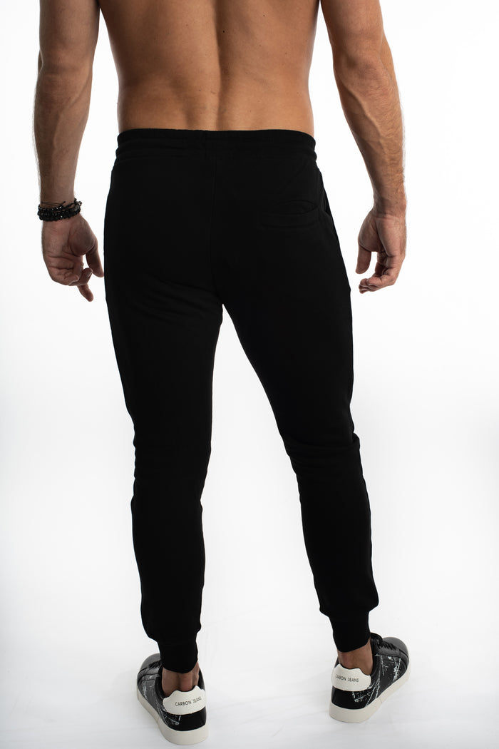 Back view of men's Carbon black streetwear joggers with a slim fit, ribbed cuffs, and back pocket on a white background.