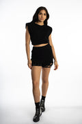 Model in Carly black high-waisted denim shorts with silver chain hardware and distressed hem streetwear style.