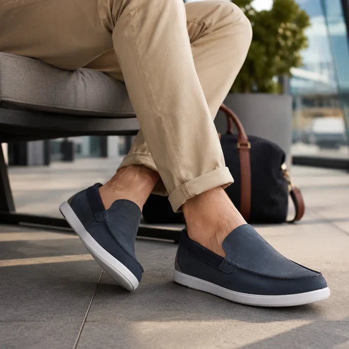 Men's navy slip-on loafer shoes with white sole, worn with light pants