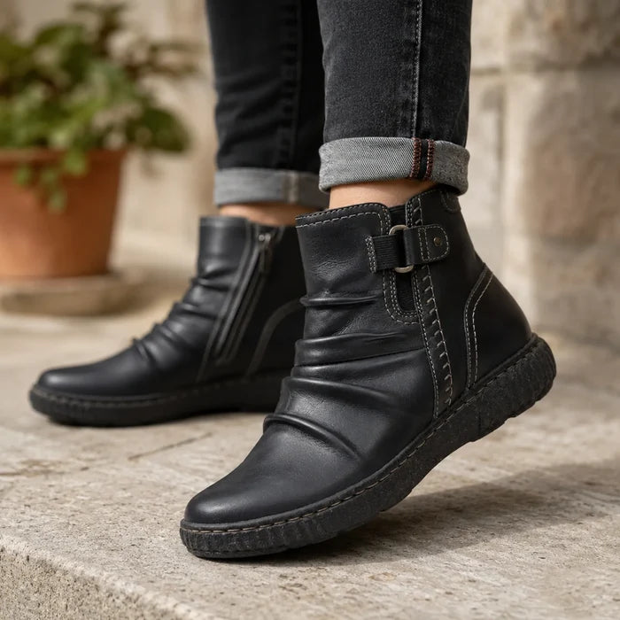 Black leather ankle boots with buckle strap, worn with jeans, chunky rubber sole