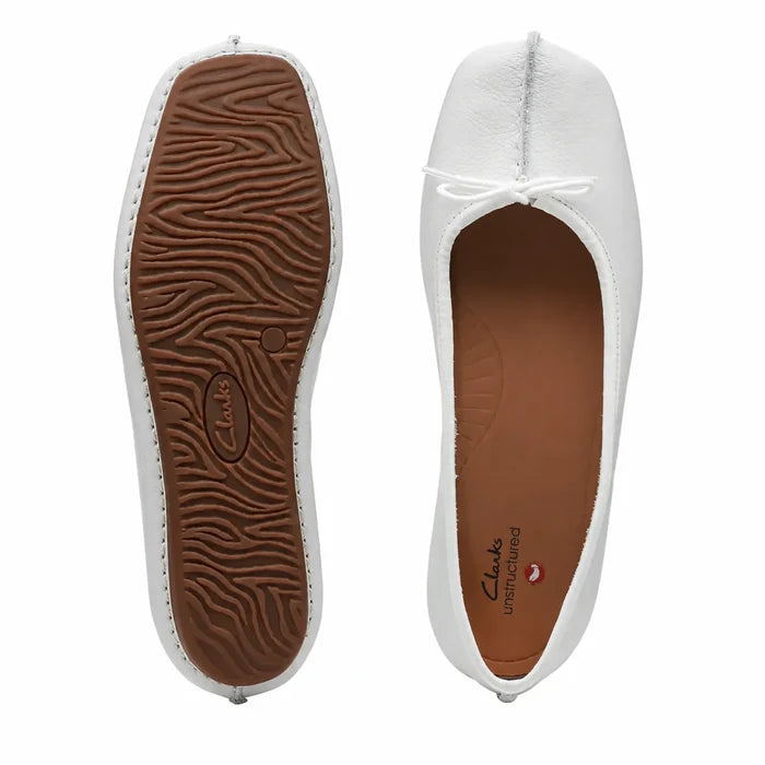 Women’s white leather ballet flats showing outsole tread and lace-up toe opening.