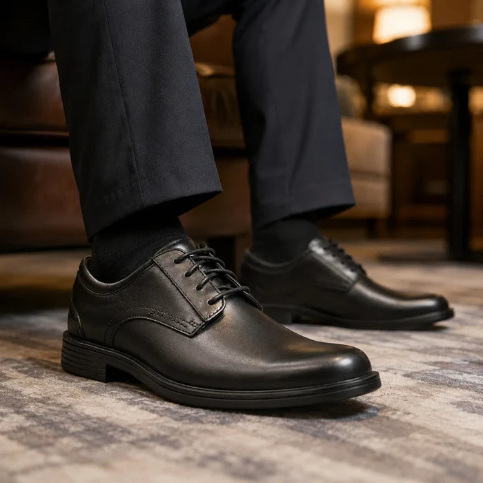 Black leather lace-up business shoes with textured sole, close-up side view.
