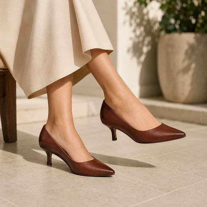 Women's brown heeled court shoes on a model with a cream skirt hem