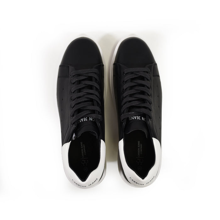 Top view of Carbon Jeans black low-top sneakers with white heel tabs and matching black laces on a white background.