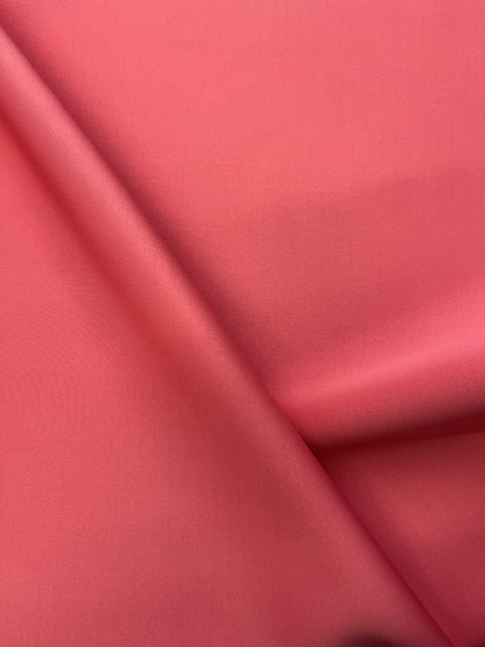 A close-up image of coral-colored scuba knit fabric.