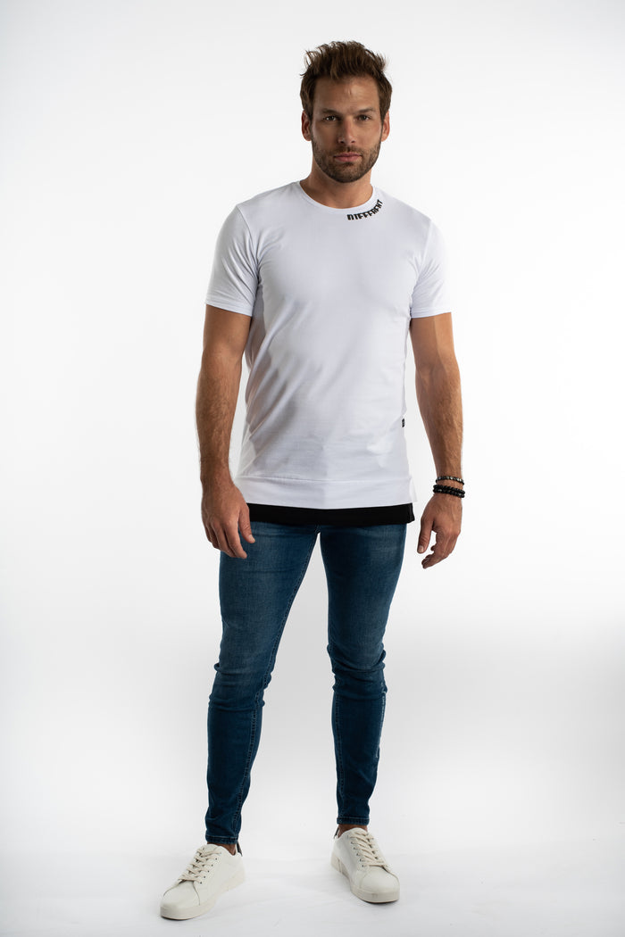 Men's white Different Tee streetwear shirt with embroidered collar, layered hem, slim jeans, and white sneakers.