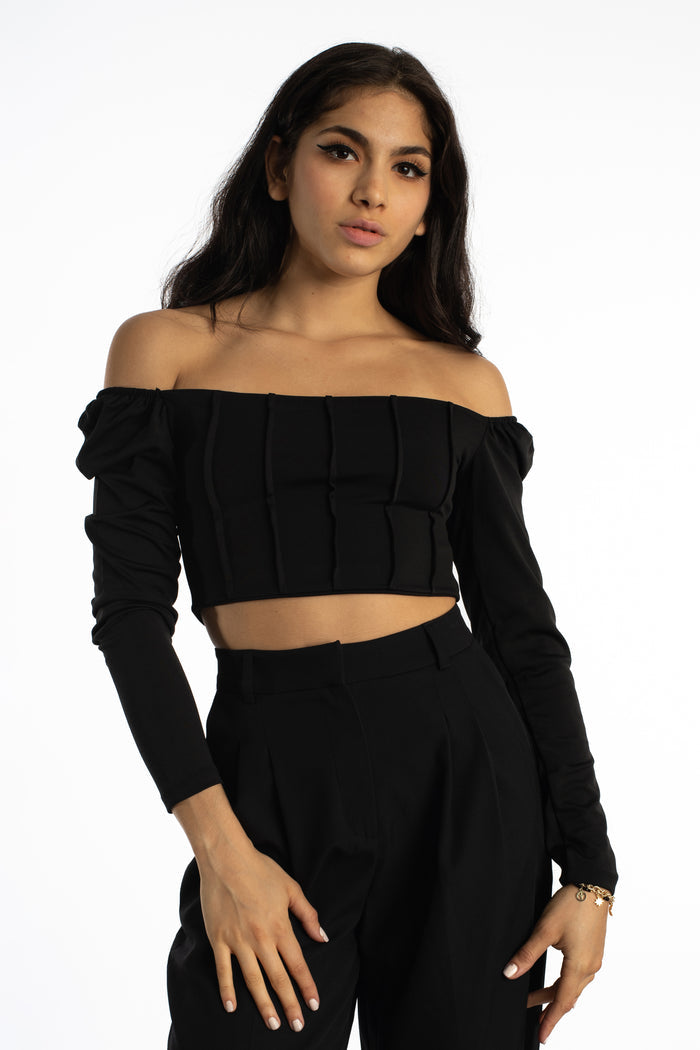 Model in Dulce black off-the-shoulder bodysuit with long sleeves and corset-style ribbing, streetwear aesthetic.