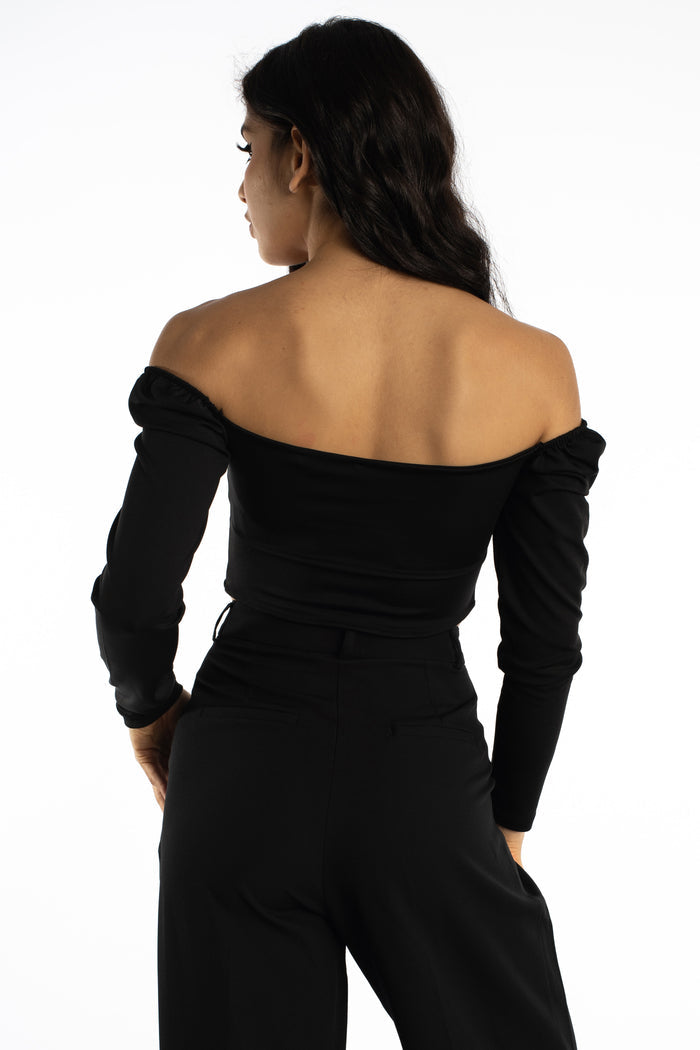 Back view of the Dulce off-the-shoulder black bodysuit with long sleeves, paired with black trousers.