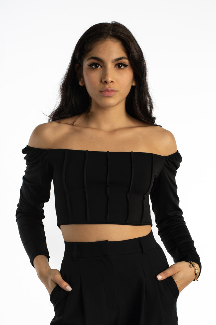 Model wears the Dulce black off-the-shoulder bodysuit in Carbon with corset ribbing and long sleeves.