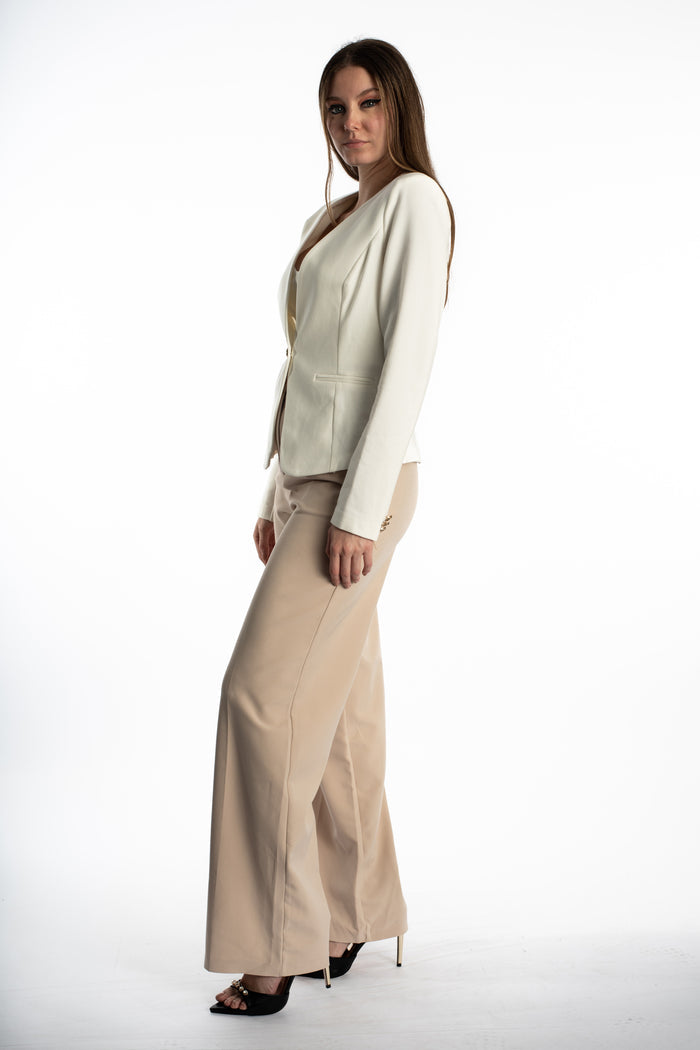 Side view of woman wearing the Eden white one-button blazer with beige wide-leg trousers and black heels.