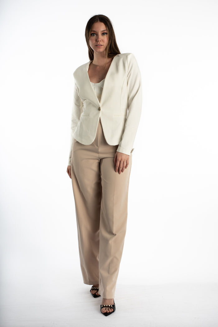Model wearing the Eden white one-button blazer with a tailored fit and tan trousers in a front-facing studio shot.