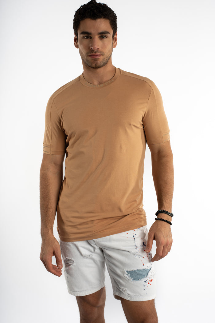 Man in a tan Element Essential Streetwear Tee with embroidered collar and sleeve details.