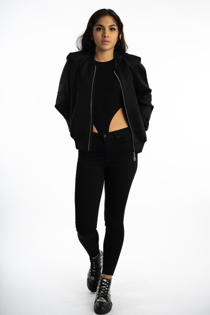 Model in Ellis Bomber Jacket Carbon black, cutout bodysuit, and skinny jeans. Streetwear aesthetic outerwear.