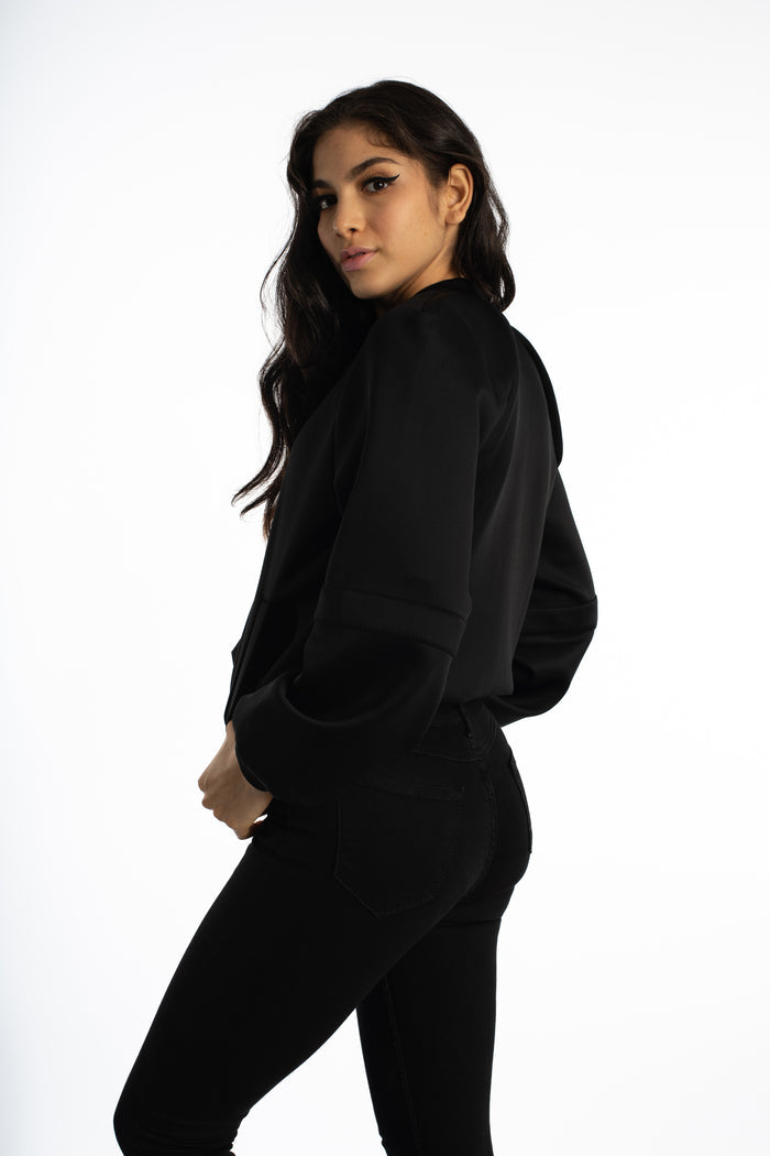 Side view of a woman wearing the black Ellis Bomber Jacket in Carbon, a sleek streetwear essential with a modern silhouette.