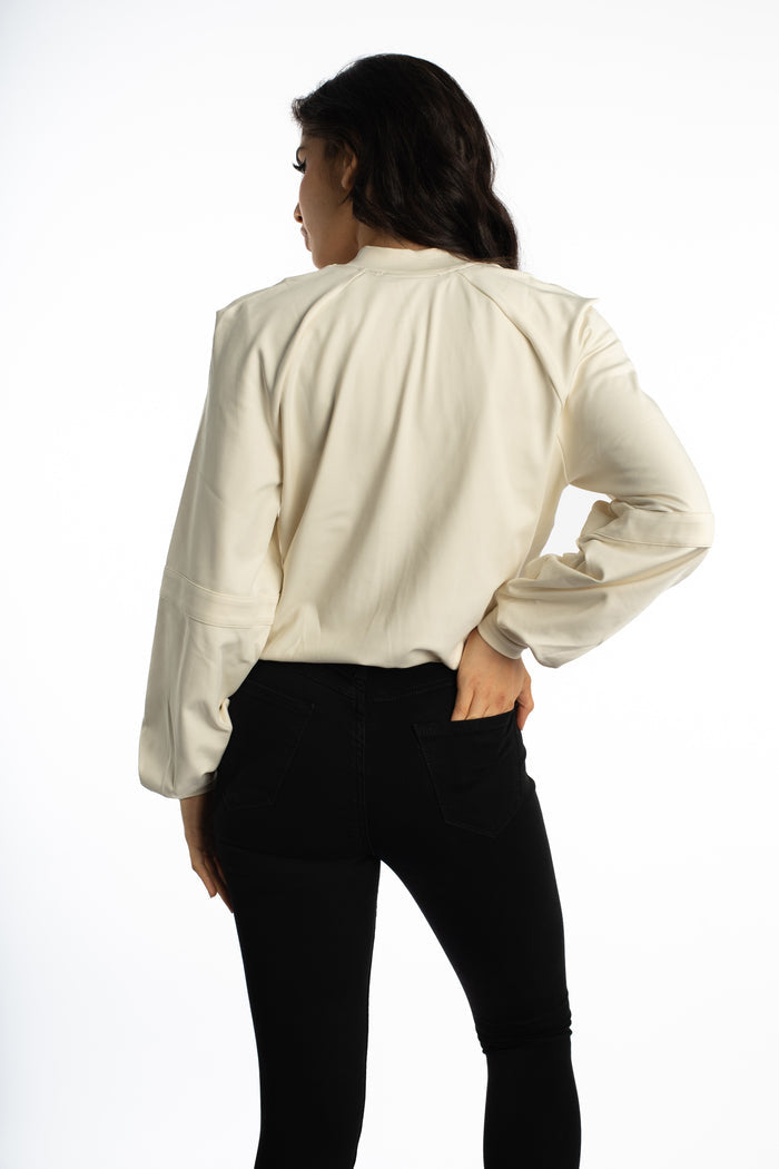 Back view of a woman wearing the cream Ellis Bomber Jacket, a streetwear essential with an oversized urban fit.