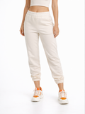 Light beige joggers with an elastic waistband, styled with a cropped top and sporty sneakers.