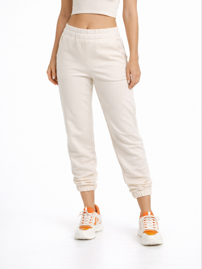 Light beige joggers with an elastic waistband, styled with a cropped top and sporty sneakers.