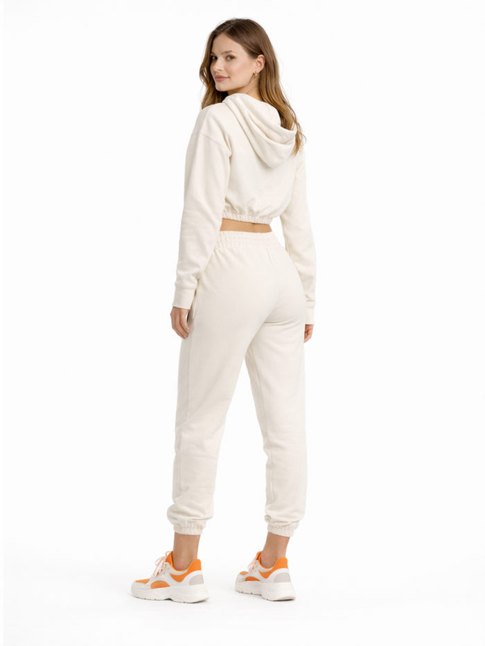 A woman in a cropped hoodie and joggers, showcasing a relaxed fit and paired with sporty sneakers.