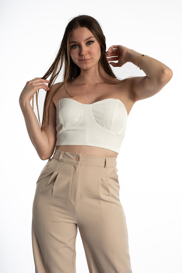 Model wearing the white Emmie Strapless Bustier Top with a structured bodice and tan pleated trousers.