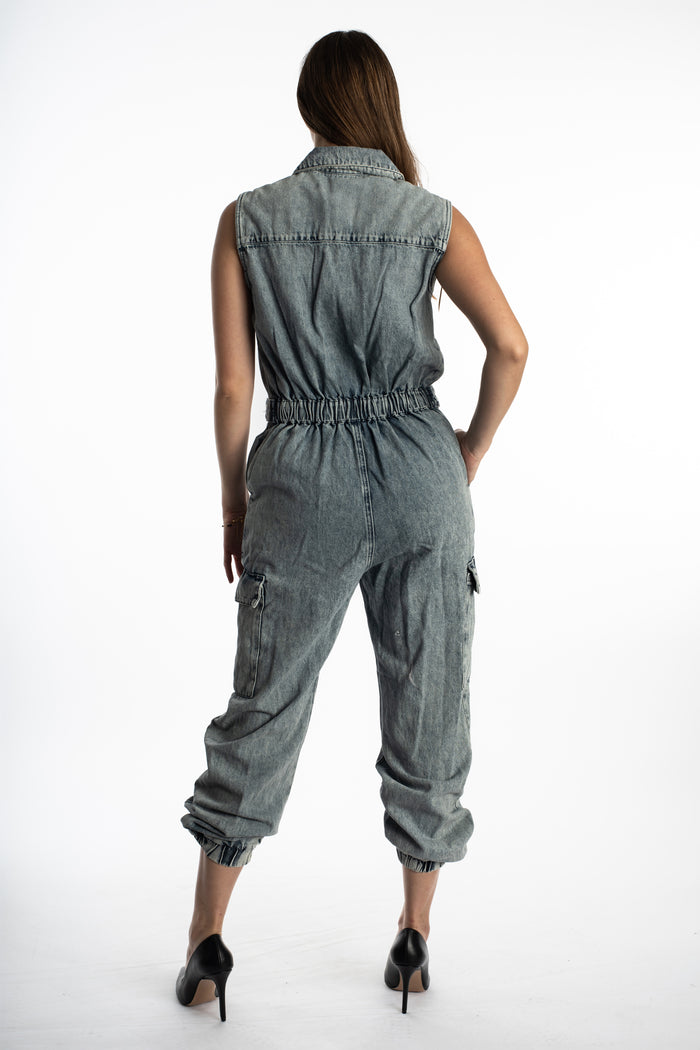 Back view of Faye Denim Jumpsuit in blue wash utility style featuring an elastic waist, cargo pockets, and tapered legs.
