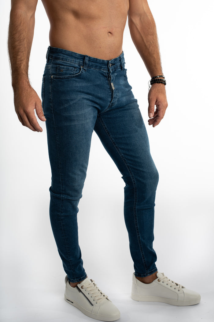 Model wearing Carbon Finn slim fit blue denim jeans and white sneakers for a modern streetwear look.