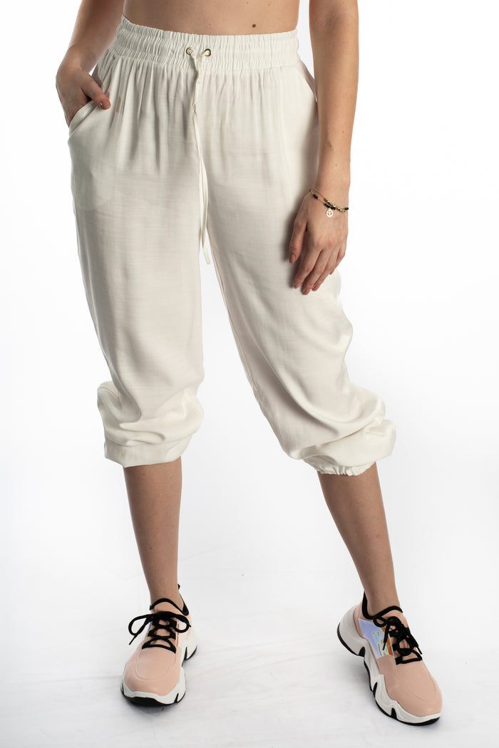 White Freya wide-leg pants featuring a high-waisted smocked drawstring and elastic cuffs on a model.