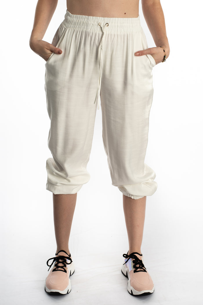 Freya high-waisted white wide-leg pants with drawstring waist and elastic cuffs, styled with pink sneakers.