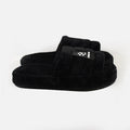 Carbon Cloud-Soft black furry slippers with plush faux fur, padded slides, and a branded logo patch on a white background.