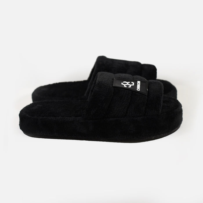 Carbon Cloud-Soft black furry slippers with plush faux fur, padded slides, and a branded logo patch on a white background.