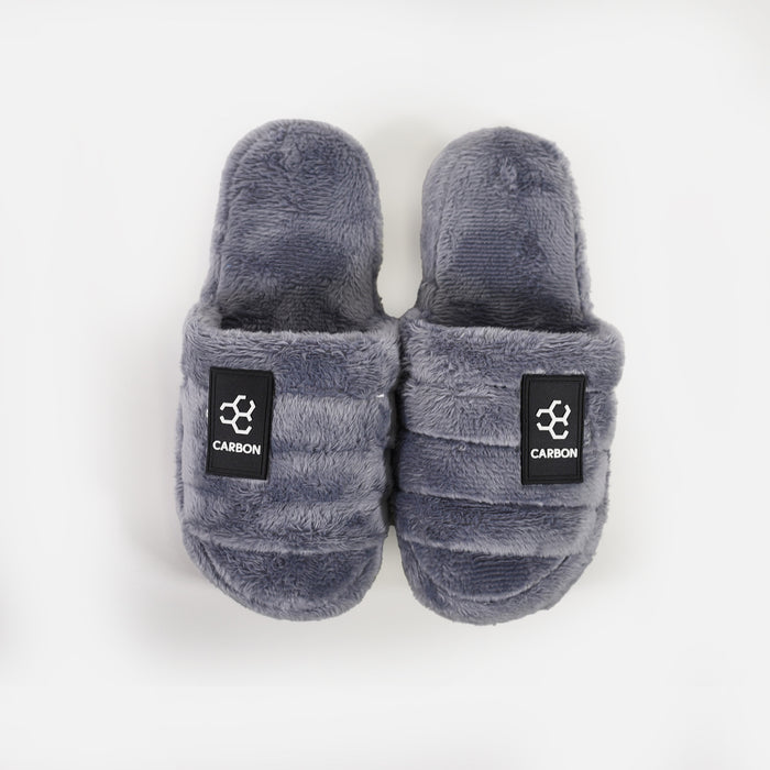 Cloud-Soft Furry Slippers by Carbon in grey faux fur with a cozy open-back design and black logo patch.