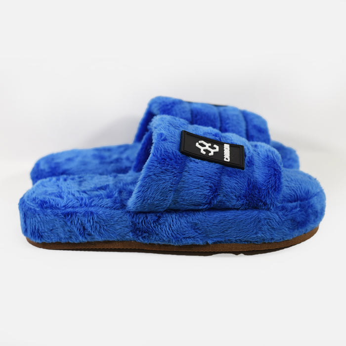 Carbon brand blue fuzzy faux fur slippers with plush cloud-soft straps, black logo patch, and durable rubber soles.