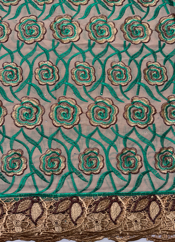 A detailed view of Swiss cotton voile lace fabric featuring a pattern with floral motifs in forest-green, brown, and gold colors.