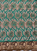 A detailed view of Swiss cotton voile lace fabric featuring a pattern with floral motifs in forest-green, brown, and gold colors.