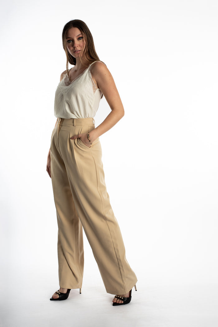 Model wearing Hallie white lace tank top with floral overlay tucked into tan wide-leg boho trousers and black heels.
