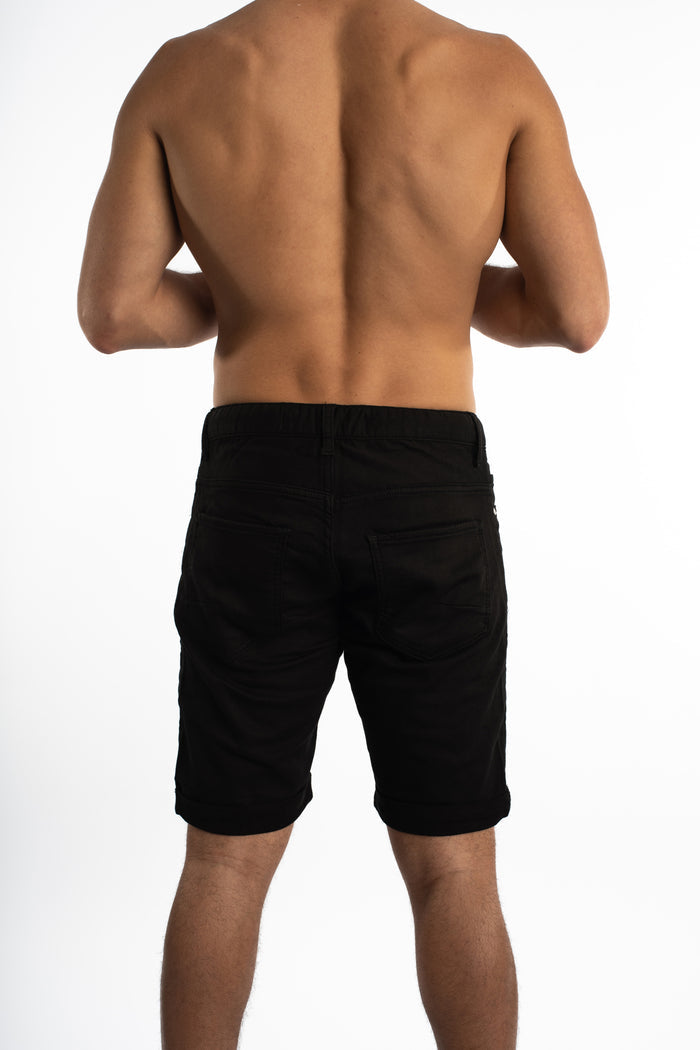 Rear view of Hank Black Denim Shorts in a slim fit on a male model, featuring back pockets and cuffed hems.