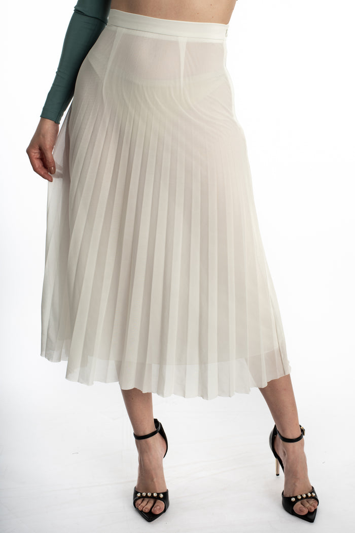 Model wearing the Jada Skirt, a white high-waisted pleated midi skirt paired with black strap heels.