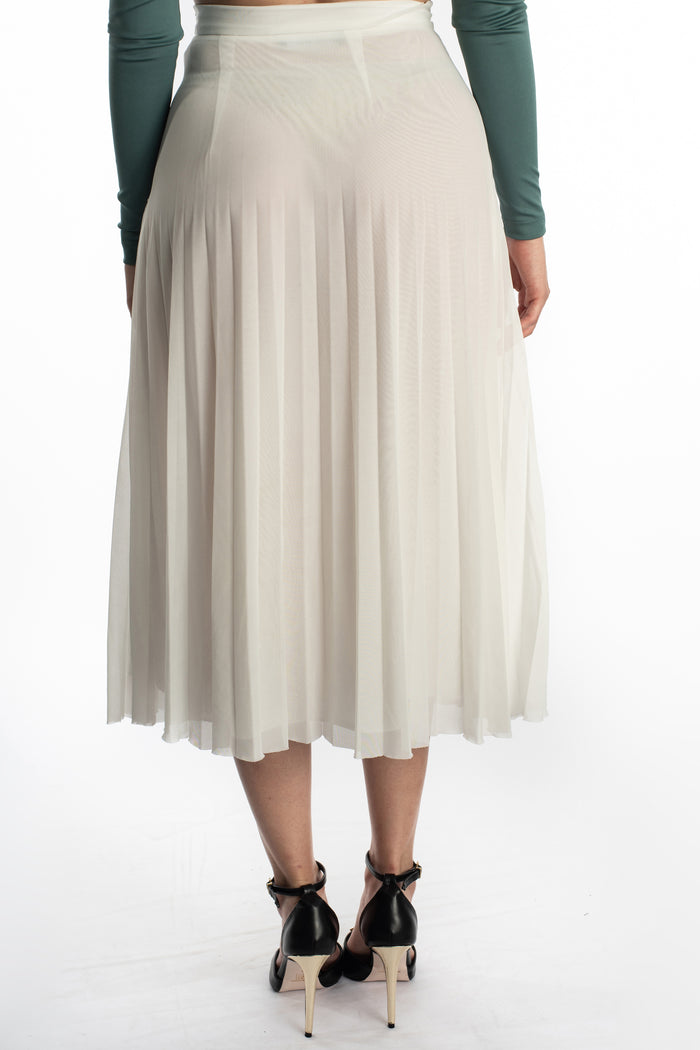 Back view of the Jada Skirt, a white high-waisted pleated midi skirt styled with a green top and black heels.