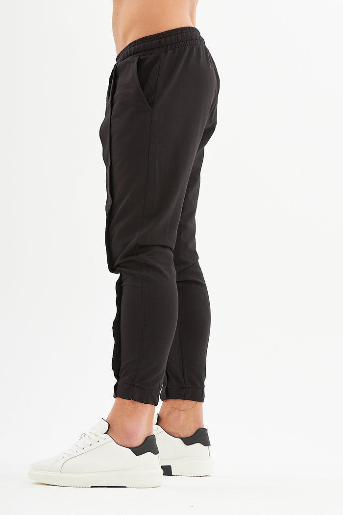 Side view of Carbon James Black Denim Streetwear Pants featuring an elastic waistband and tapered cuffed ankles.