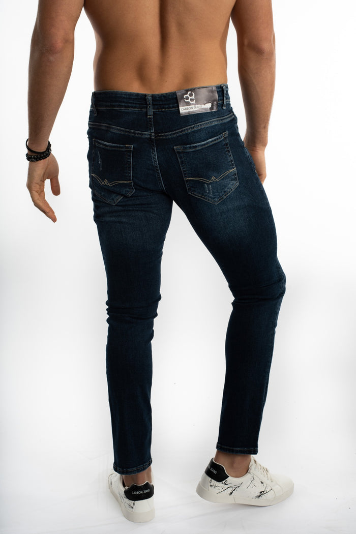 A man wearing dark denim jeans and white sneakers, showcasing the back view and pocket details.